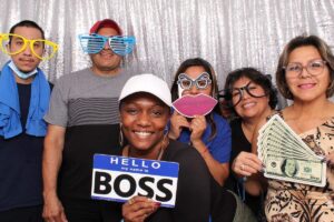 A group of staff taking a photo in a photo booth with props.